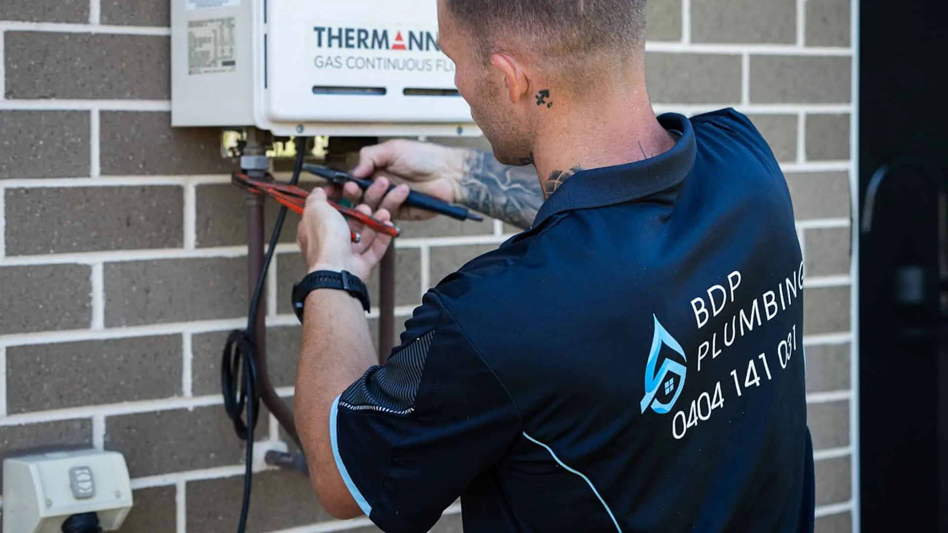 Plumber servicing a continuous-flow gas hot water unit
